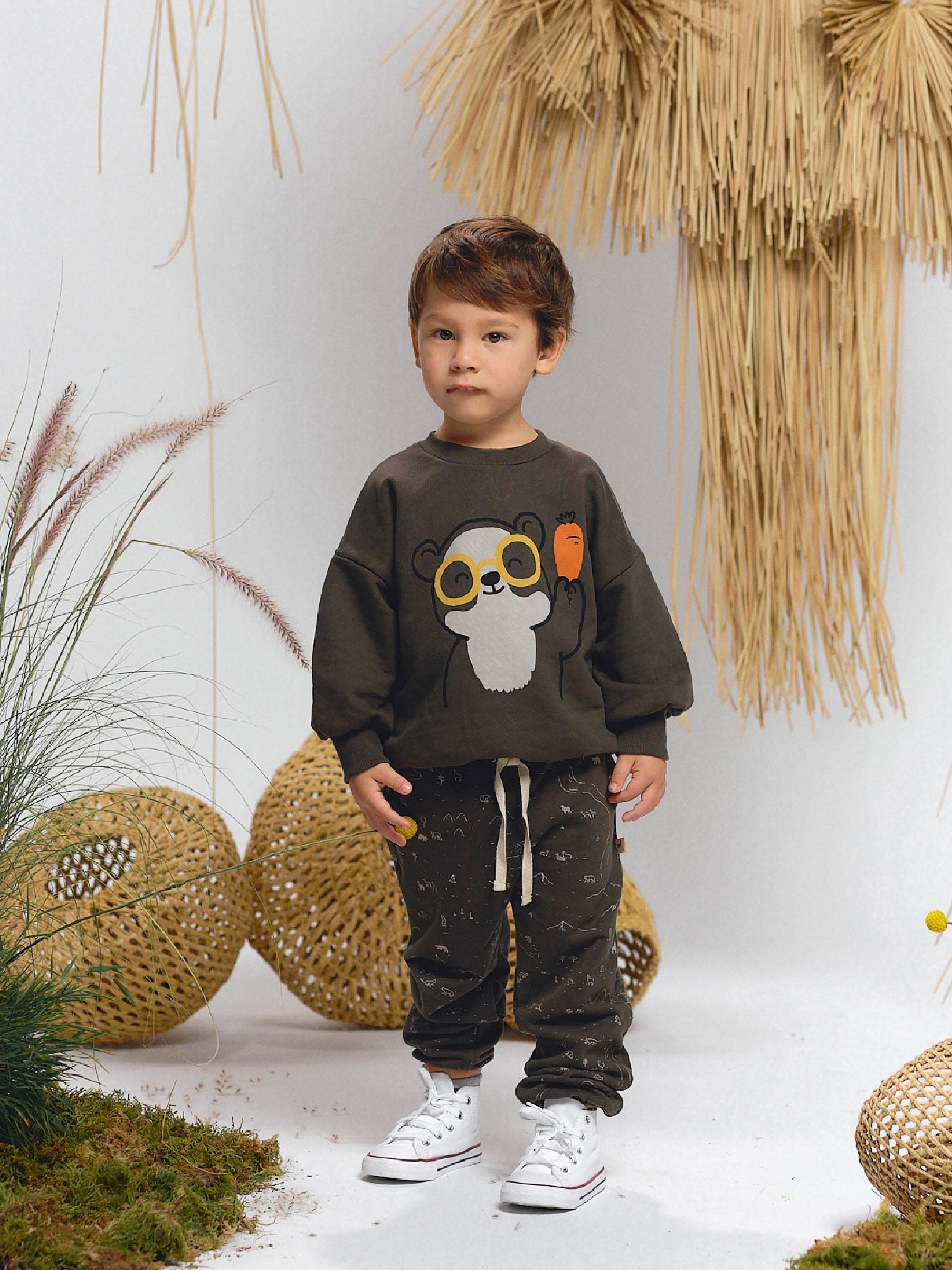 Dark gray sweatshirt featuring a spectacled bear holding a carrot, paired with matching pants with subtle animal line motifs.