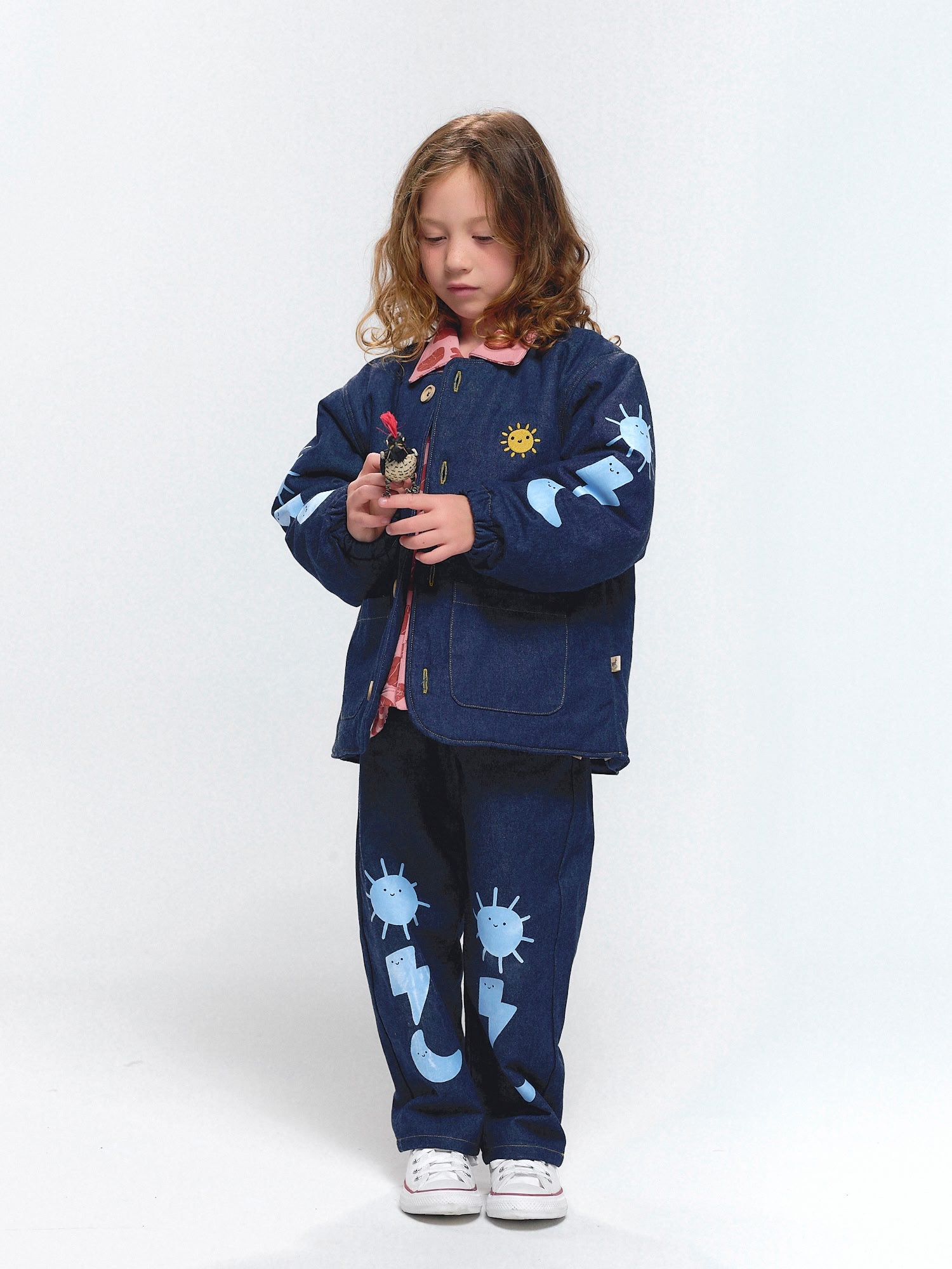 Denim coat and pants featuring playful sky-inspired motifs with suns, moons, and thunderbolts.