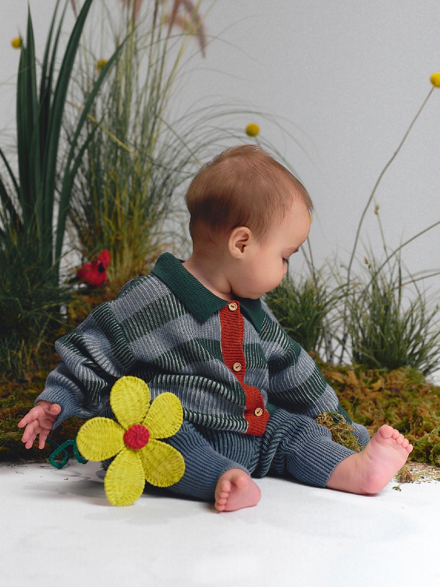 Buttoned cardigan with collar in green, blue, and red stripes, paired with blue knit pants.
