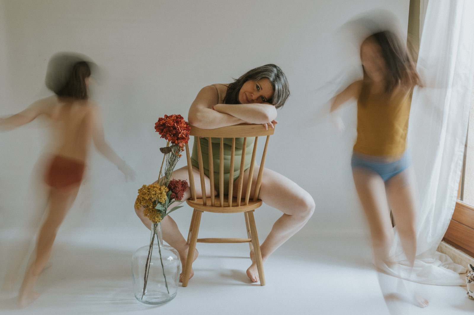 Cristina Pujol Photography. Mother in the middle. Seated. two children dancing next to her