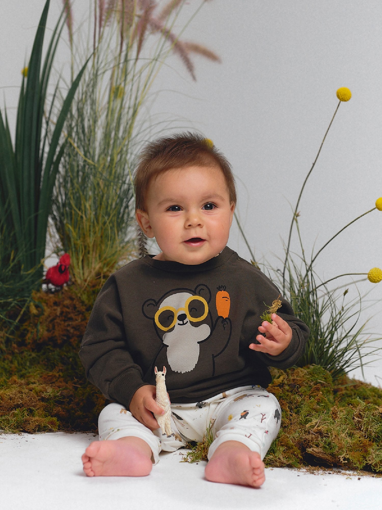 Dark gray sweatshirt with spectacled bear holding a carrot, paired with cream pants with scattered prints.