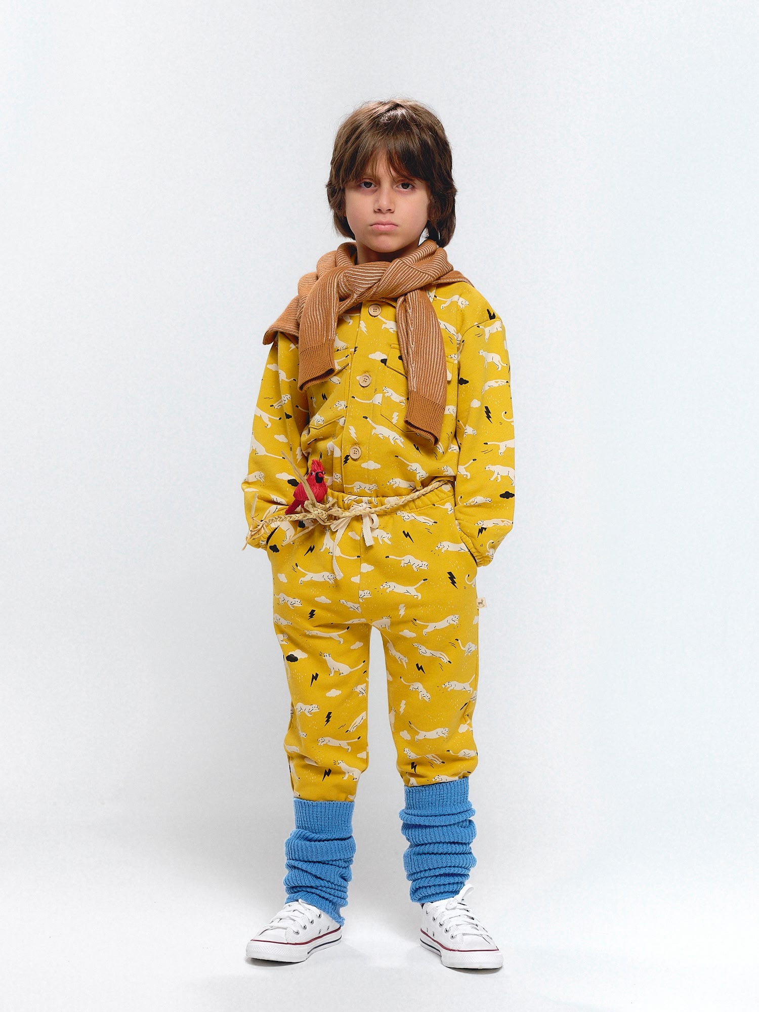 Child dressed in a mustard outfit covered with dynamic puma and thunderbolt prints.