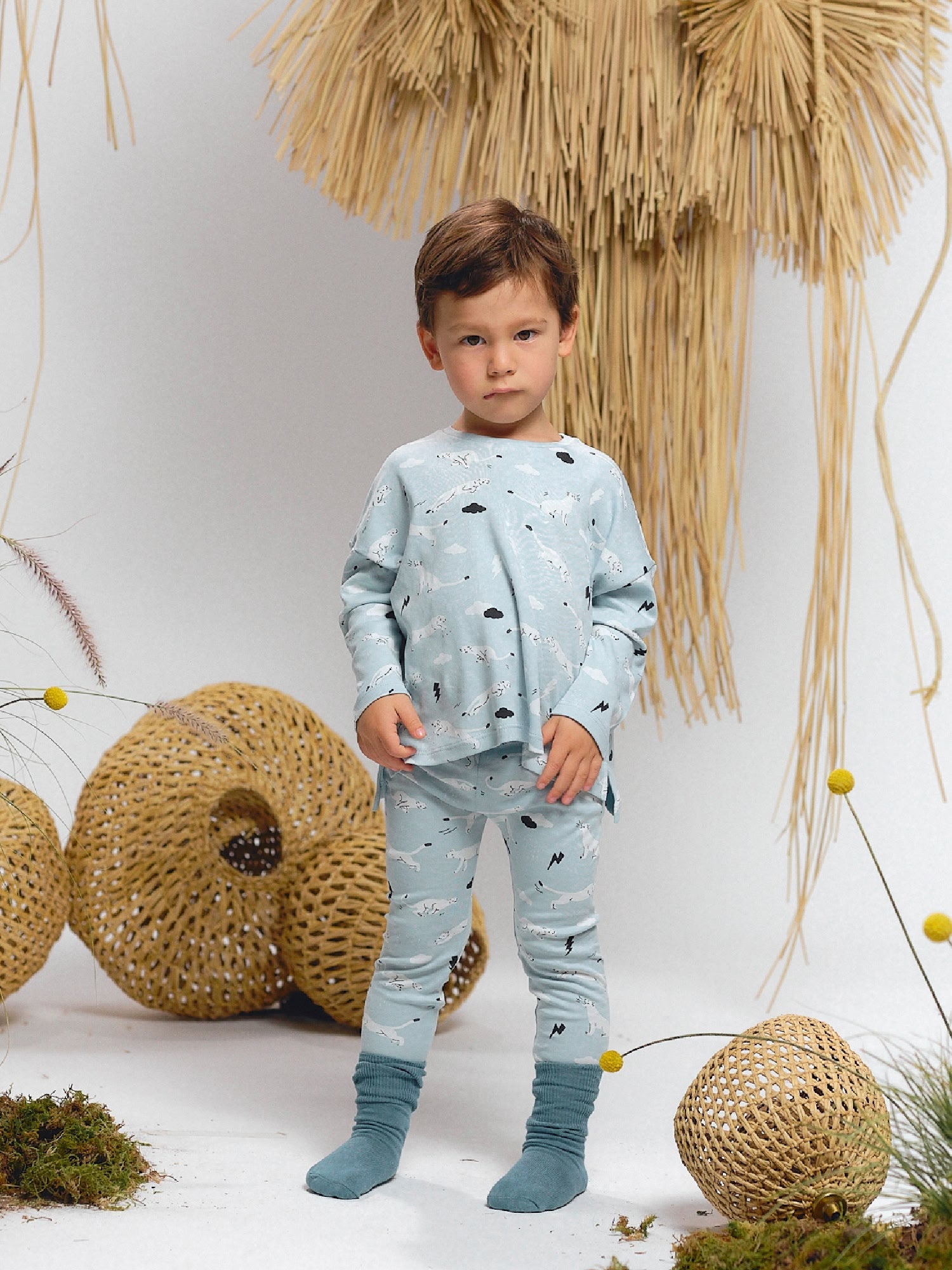 Boy wearing light blue long-sleeve T-shirt and leggings set with Thunder Puma print (pumas and lightning). Styled with teal socks.